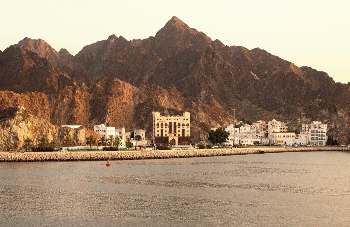 El malecón de Muscat al atardecer con las rocosas montañas Hajar detrás de los edificios blancos