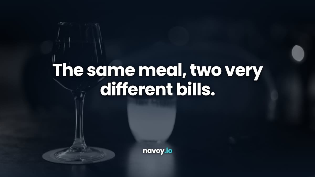 A glass of red wine and a candle on a dark restaurant table, photographed in black and white