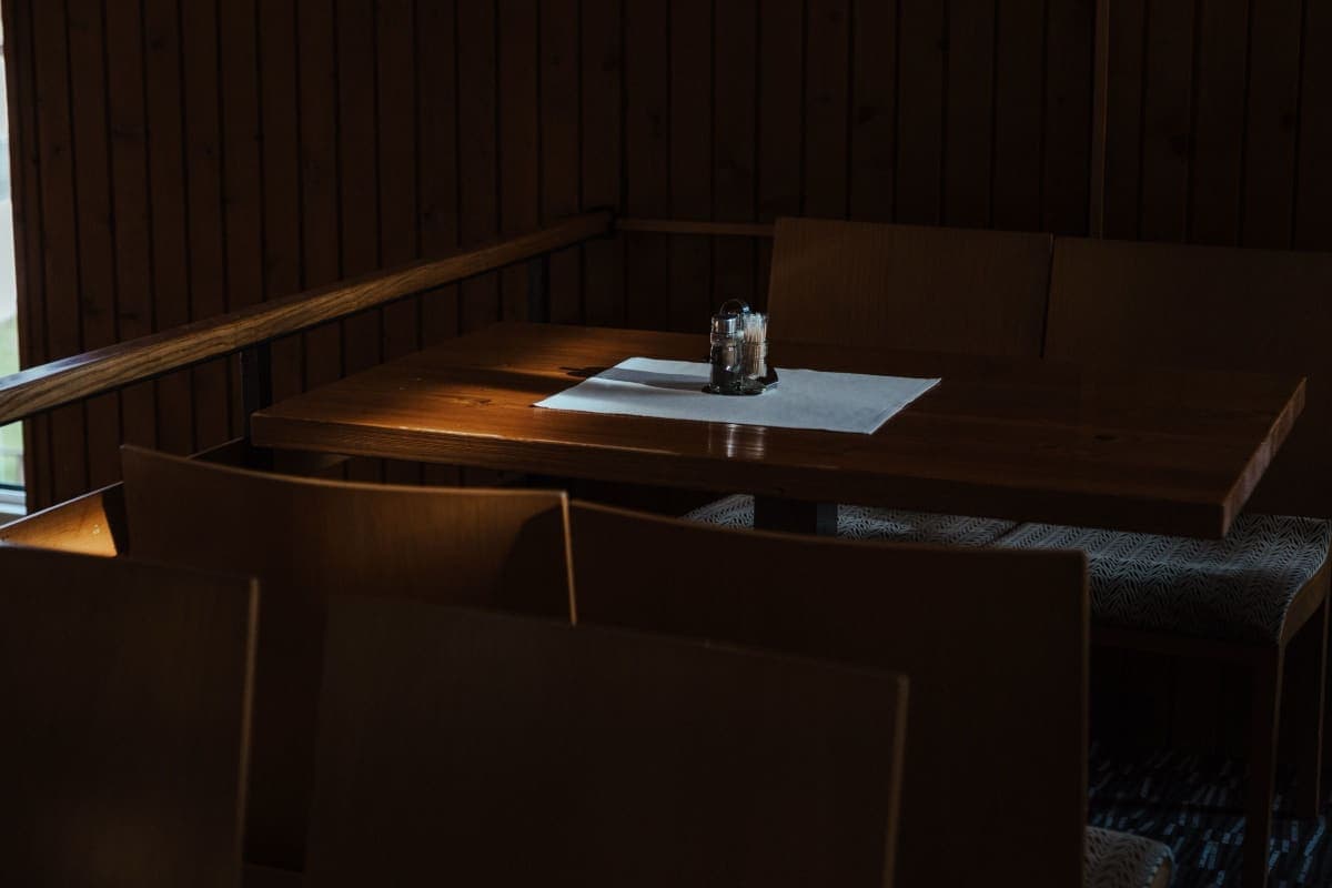 A person reading a menu at a European restaurant table, no legible text visible