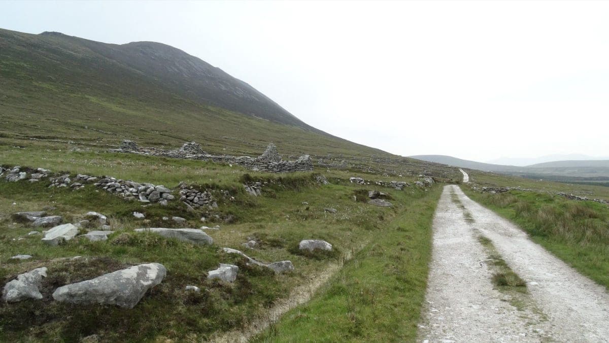 Roofless stone cottage ruins at the Slievemore deserted village on Achill Island, Ireland, under an overcast sky
