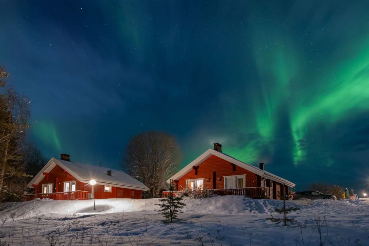 Cabañas de madera roja bajo las auroras boreales en la Laponia finlandesa