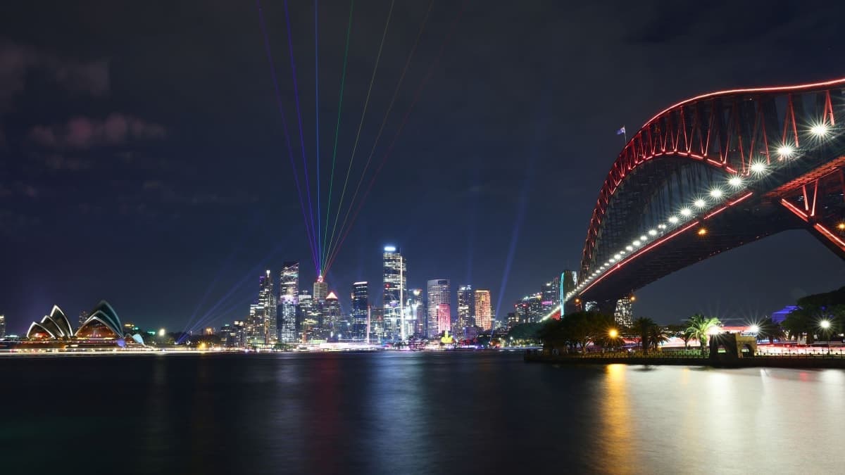 Sydney Harbour at night with the Opera House, the city skyline and the Harbour Bridge lit up over the water
