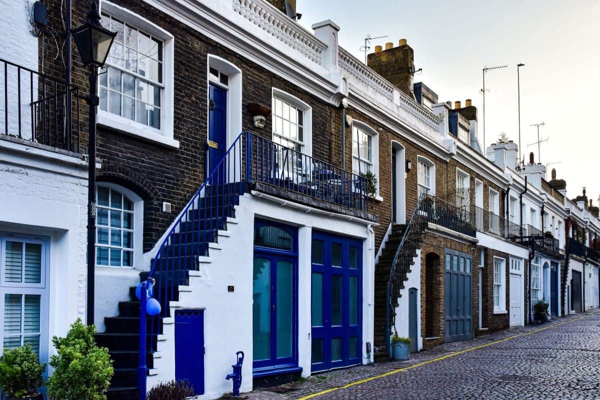 A row of stone terraced buildings on a European city street in flat daylight, no signage visible