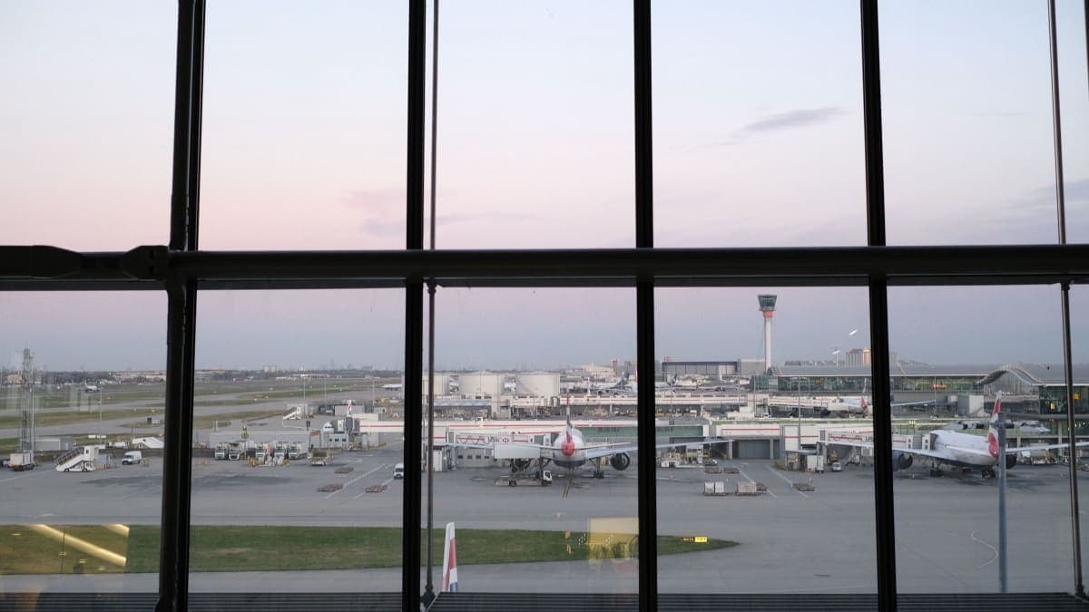 Heathrow Airport apron and control tower seen through a terminal window at dusk