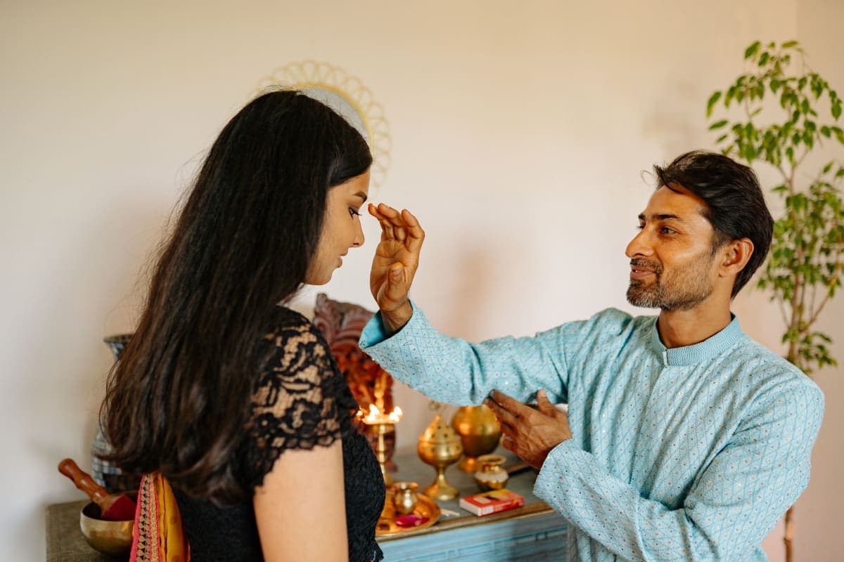 Una pareja realizando una ceremonia tradicional de Diwali con lámparas de aceite en casa